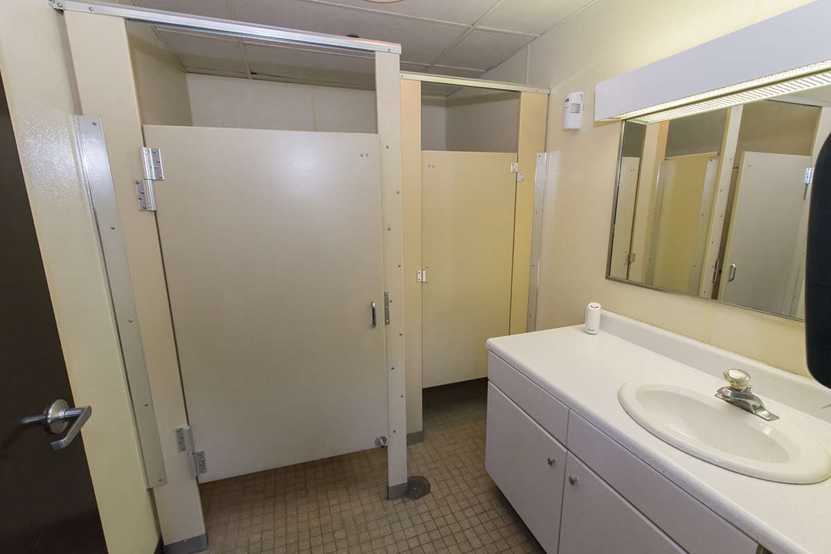 A clean bathroom with metal stall dividers.